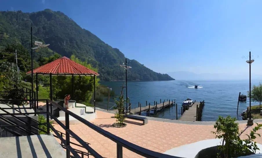 The dock at Tzununá with a boat coming in and the hillside behind it.