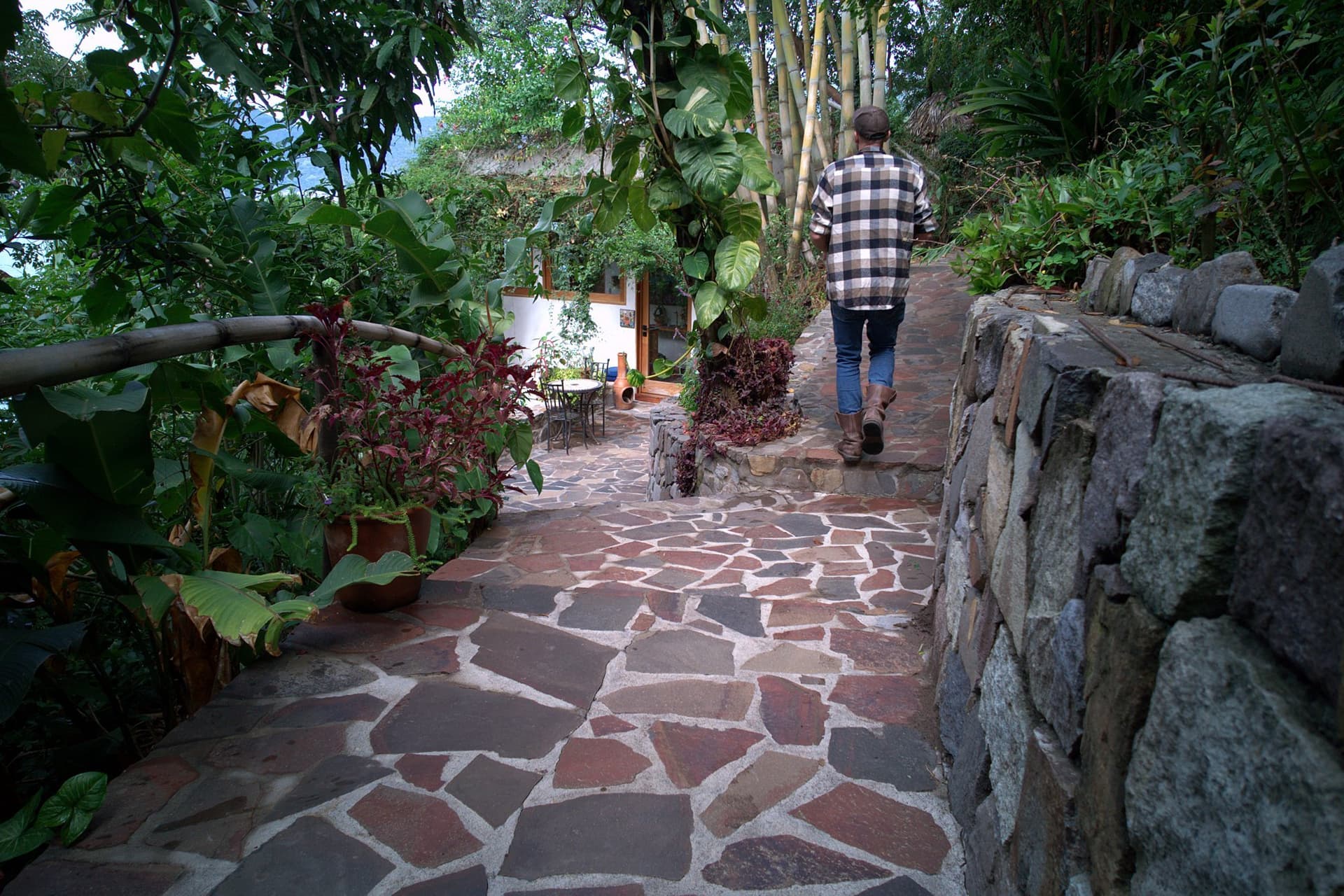 A flagstone path edged with dry-stone walls and dense planting leading down to the house at Casa Paloma, Pasajcab