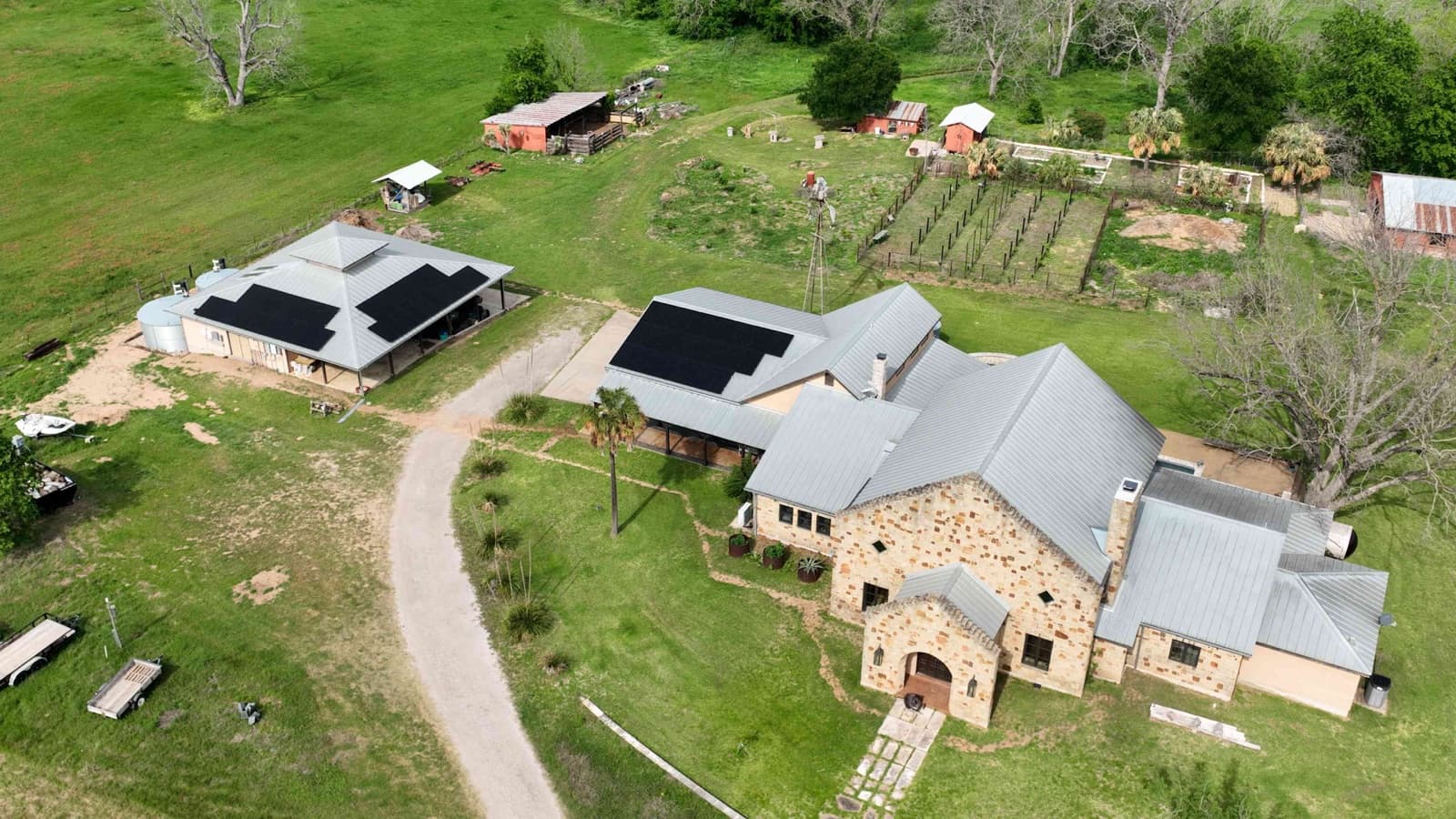 Aerial view of Kintsugi Ranch — stone house with solar, drive, and growing systems